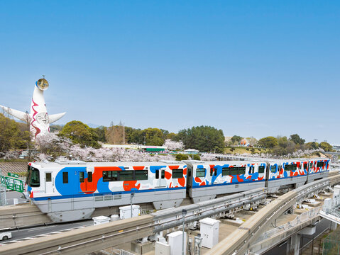 Osaka, Japan - April 7 2024: "EXPO TRAIN 2025 Osaka Monorail", designed for Expo 2025 Osaka Kansai, passing Expo '70 Commemorative Park with cherry blossoms in full bloom