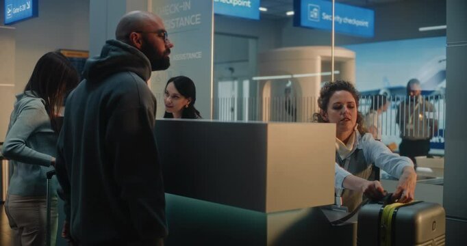 Diverse Passengers at Airport Counter: Female Airline Check-in Attendant Checking Baggage of Man, Putting Barcode Label on Suitcase for Flight. Security Checkpoint in International Airport Terminal.