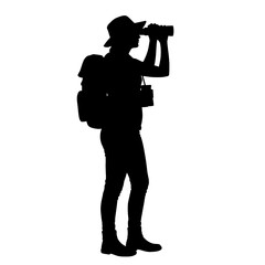 Silhouette hiker views through binoculars standing with backpack outdoors exploring nature