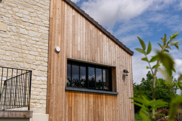 Extension moderne d’une maison avec bardage en bois, contrastant harmonieusement avec la...