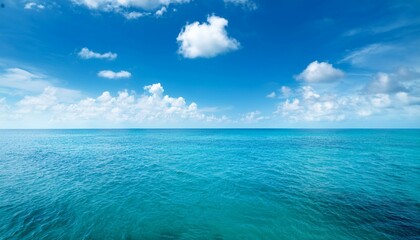 Fototapeta premium a stunning view of a calm turquoise ocean under a clear blue sky with scattered fluffy white clouds and sunlight reflecting off the water