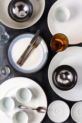 Top view of an empty plates, bowls, glasses and cutlery placed on a black chalkboard background. Flat lay. Top view. Food concept.