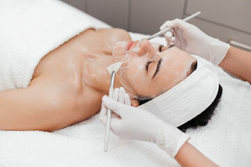 Female beautician applying cleansing foam on woman face. Cosmetology procedure in beauty clinic. Attractive Young Female Enjoying Skincare Treatments, Copy Space. Advertising banner