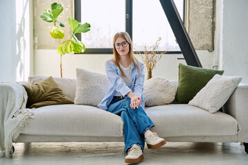 Obraz premium Portrait of young beautiful smiling woman looking at camera sitting at home on sofa