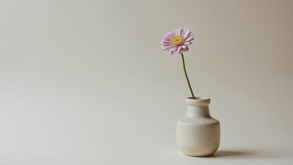 Minimalistic still life composition showcasing a single flower in a simple ceramic vase on a soft neutral background
