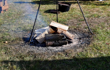 A close up on a freshly lit bonfire with the fuel being logs, planks, and boards, with a small grate or metal frame to be used later to cook food for the participants of medieval fair in Poland