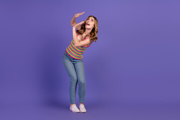 Young woman in casual attire posing playfully against a purple background, expressing vibrant...