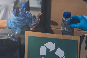 Close-up of female hands from a family collecting plastic waste and bottles from the ground. They...