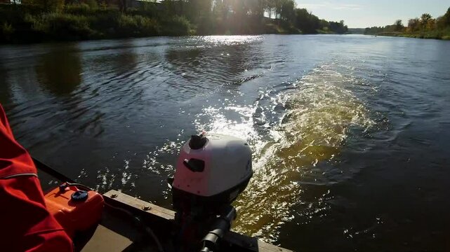 A man steers a boat with a motorboat engine while traveling down a river. A Motorboat or Powerboat is a Boat that is Exclusively Powered by an Engine. Faster Examples May be Called Speedboats.