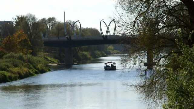 A Small Tourist Boat is Sailing Along the River Under the Bridge in Autumn. Valmiera is One of the Oldest Cities in Latvia, Having Been a Member of the Hanseatic League.