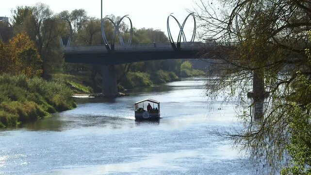 A Small Tourist Boat is Sailing Along the River Under the Bridge in Autumn. Valmiera is One of the Oldest Cities in Latvia, Having Been a Member of the Hanseatic League.