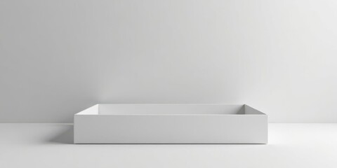 Empty white rectangular box on a minimalist surface against a simple backdrop