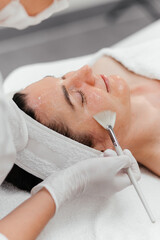 Close-up Cosmetologist cleaning face of a middle aged caucasian woman with special gel before...