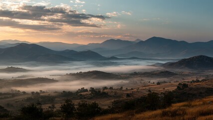 Obraz premium Mountain range shrouded in fog at sunrise, atmospheric landscape. 