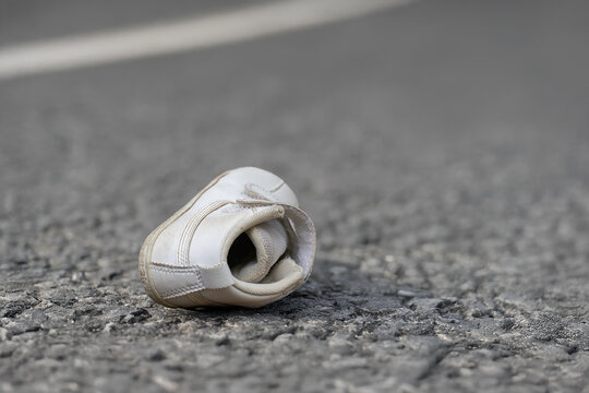 アスファルトの道路に落ちている子供の小さな靴