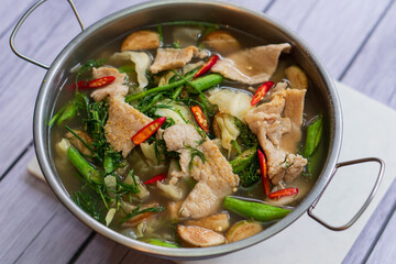 Spicy soup with mushrooms, lemon, coconut milk and chili in white bowl on wooden table background.