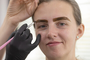 Woman is getting her eyebrows done by makeup artist.