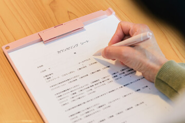 カウンセリングシートに書き込む女性の手元
