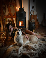 alternative Frau mit ihrem Hund auf dem Lammfell vor dem Kamin 