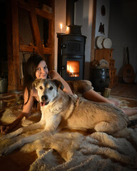 alternative Frau mit ihrem Hund auf dem Lammfell vor dem Kamin 