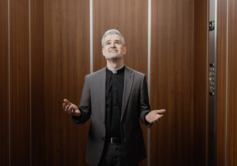 Serene priest praying in the elevator