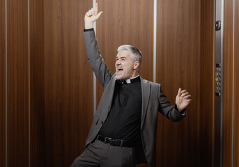 Cheerful priest singing and dancing in the elevator © stokkete