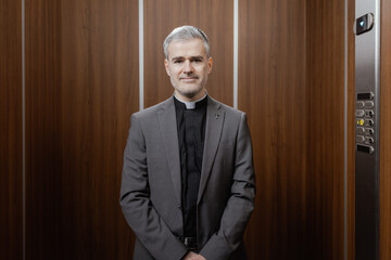 Portrait of a smiling priest standing in an elevator