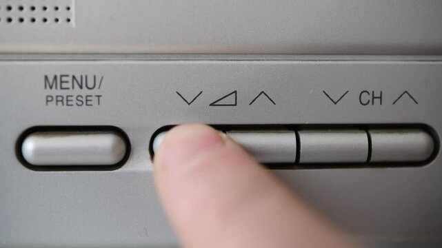 Close-up of finger adjusting volume on old TV.