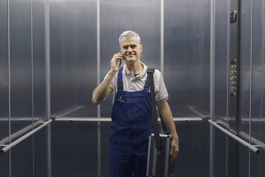 Technician standing in the elevator and having a phone call