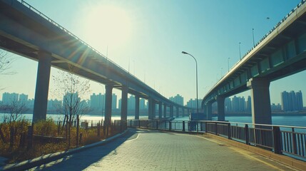 Obraz premium Road view under two bridges with city skyline and bright sunlight.