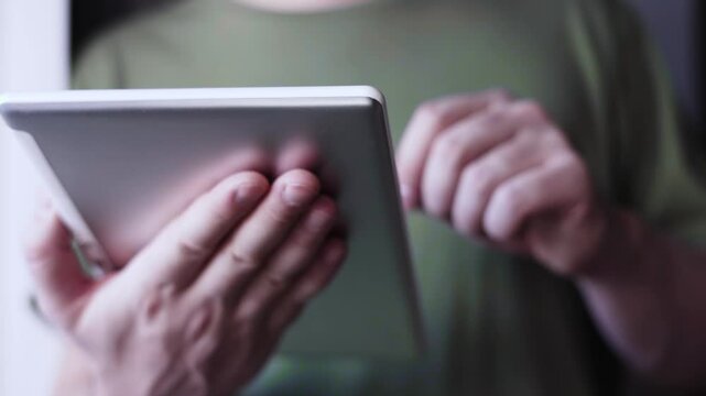 A man holding a tablet and engaging in creative hobbies like drawing or photography in a cozy home environment, showcasing the versatility of modern technology 