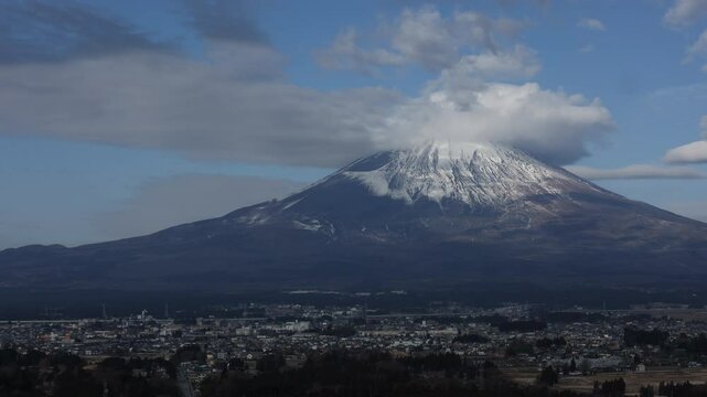 Timelapse of mount Fuji in Japan with snow at the top of mountain in blue and cloudy sky.