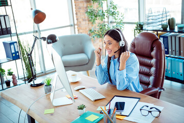 Excited female professional celebrating success while working in a modern office interior with...