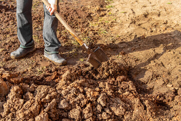 A man digs up the ground with a shovel. Clay soil