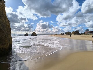 Dark, swirling clouds gather above the rocky shore, casting shadows over the wild, untamed ocean.