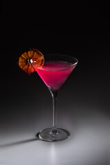 cold cosmopolitan cocktail with dried orange slice, on dark shadowy background, stock