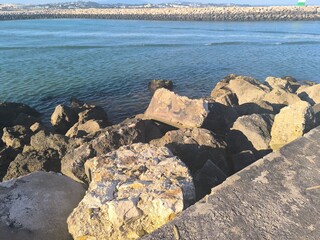 A serene sunset unfolds at a rocky cove, where the colors of the sky reflect off the ocean and illuminate the coastline.