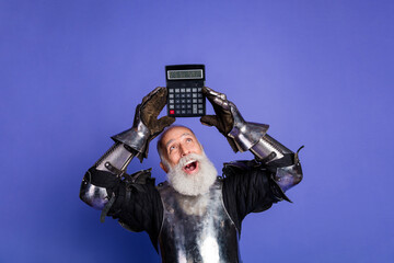 Elderly man in medieval knight armor holding calculator with a joyful expression against a vibrant...