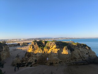 The sunset casts its light over the rocky coastline, enhancing the shapes and textures of the coastal rocks.