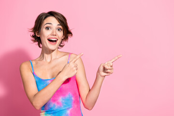 Charming young woman pointing excitedly against a vibrant pink background in casual summer fashion