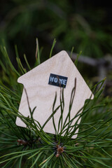 Wooden house in forest on pine branch with inscription home.