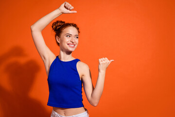 Smiling Young Woman in Casual Blue Top and Stylish Hair Gesture Against Bright Orange Background...