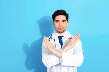 Confident male doctor in white coat with arms crossed posing against a bright blue background representing medical care and professionalism