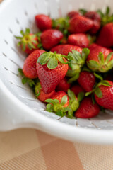 Freshly washed ripe strawberries in a white colander. Soft focus photo. Healthy eating. Fresh seasonal berries. Food hygiene.