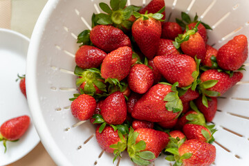 Freshly washed ripe strawberries in a white colander. Healthy eating. Fresh seasonal berries. Food hygiene.