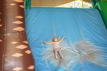 A little girl slides down an inflatable slide at a children's play park.