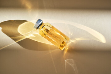 Injection vial with medicinal product in sunlight on beige background.