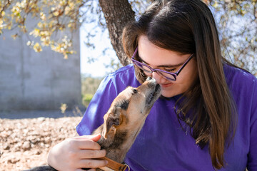 dog licks her human's nose while she smiles happily in a scene of love and animal complicity.