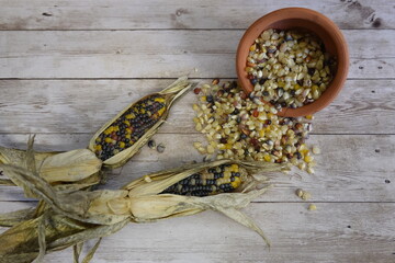 Glass gem corn kernels spilling from terracotta bowl onto wooden table