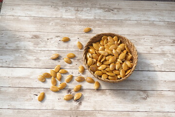Pumpkin seeds spilling from a wicker bowl on rustic wooden table